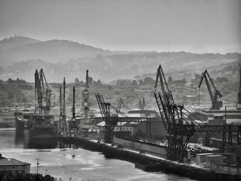 Cranes at harbor against sky