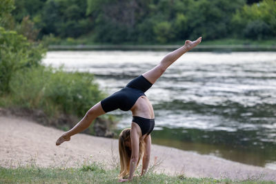 Full length of woman exercising on beach