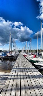 Sailboats moored at harbor against sky
