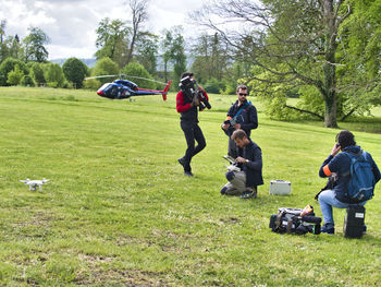 People on grassy field against trees