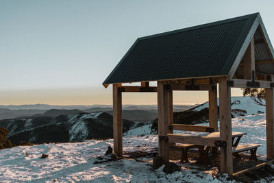 Gazebo on snow covered land against clear sky