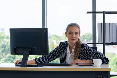 Portrait of young woman sitting on table