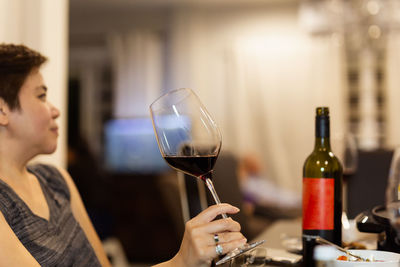 Female hand holding glass of red wine.