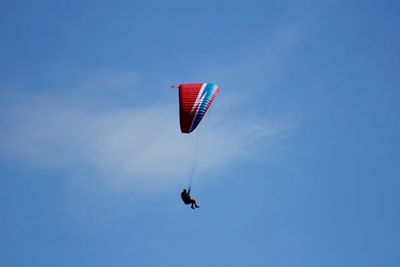 Low angle view of man paragliding against blue sky