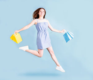 Full length of a young woman against blue background