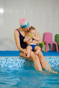 Early age swimming in pool. baby boy waiting near side, learning shapes and fruits. happy child 