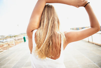 Rear view of woman stretching on footpath