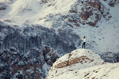 Side view of young woman standing on mountain during winter