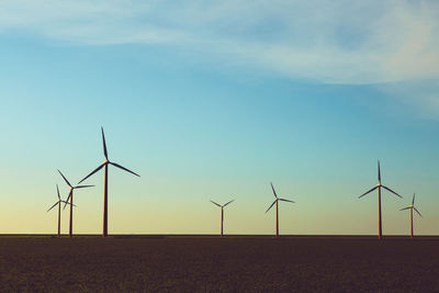 Windmills on field against sky