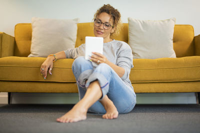 Young woman using laptop while sitting on sofa at home