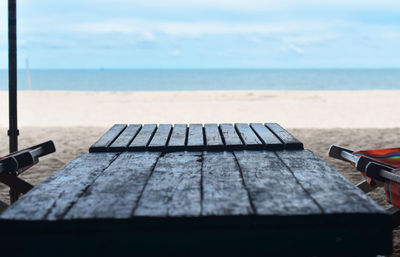 Deck chairs on beach against sky