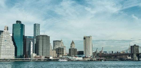 Sea by modern buildings against sky in city