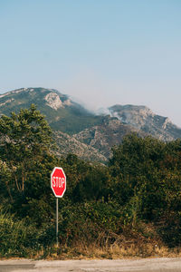 Road sign by mountains against sky