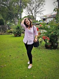 Portrait of smiling young woman standing against plants