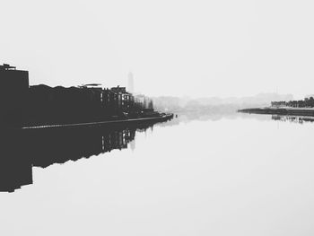 Reflection of buildings in lake against clear sky