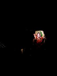 People holding illuminated lighting equipment against black background