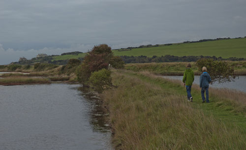 Rear view of people walking on land against sky