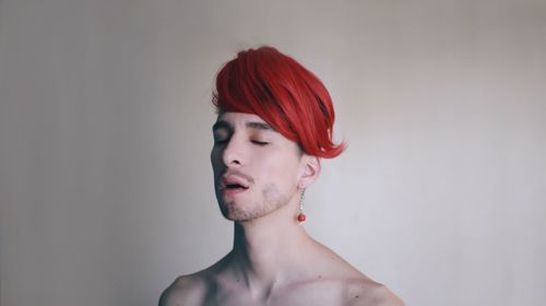 Close-up of shirtless young man against white background