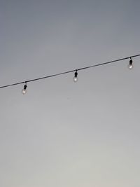 Low angle view of light bulbs against clear sky