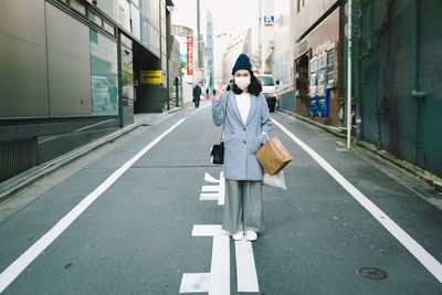 Portrait of woman wearing mask while standing on city street