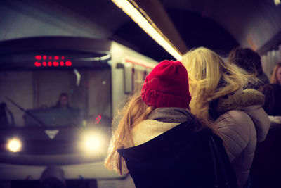 Passengers waiting for illuminated train to arrive at railroad station