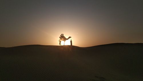 Rear view of man standing on mountain against sky during sunset