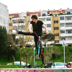 Man riding bicycle on building in city