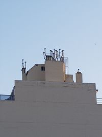 Low angle view of bird perching on building against clear sky