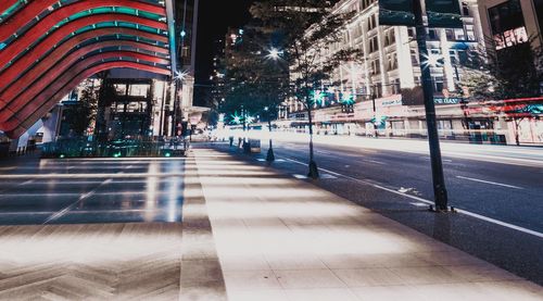 Illuminated street amidst buildings in city at night