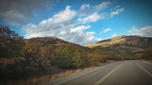 Road by mountains against sky