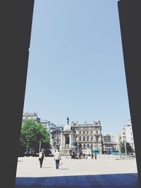 People walking in city against clear sky
