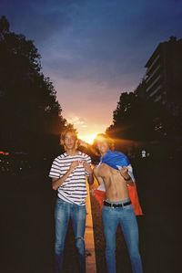 Rear view of people standing against sky during sunset