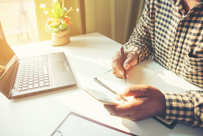 Midsection of woman using laptop on table