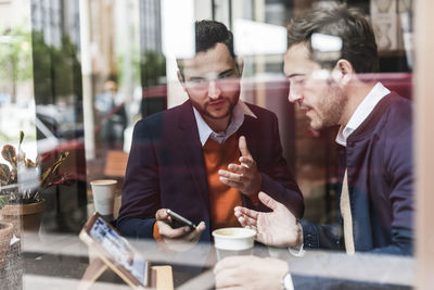 Usa, new york city, businessmen meeting in coffee shop, using mobile devices