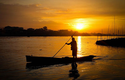 Silhouette person in sea against sky during sunset
