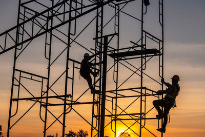 Silhouette man working at construction site against sky