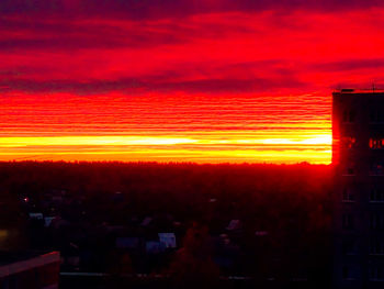 Illuminated buildings against romantic sky at sunset