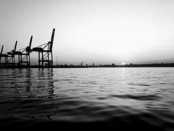 Cranes in sea against sky