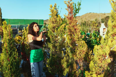 Portrait of young woman standing against plants