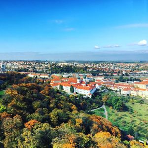 High angle view of trees and cityscape against blue sky