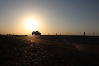 Silhouette people on road against sky during sunset