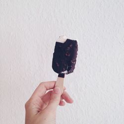 Cropped hand holding ice cream over white background