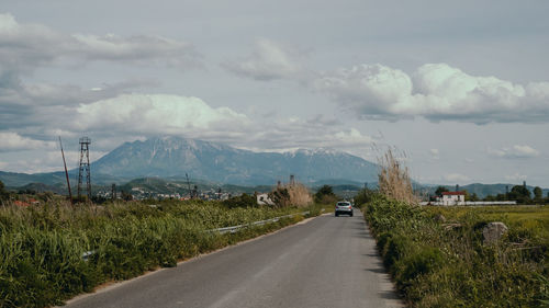 Road leading towards mountains against sky