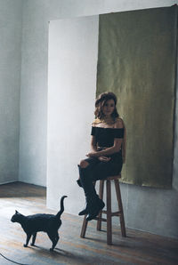 Full length portrait of young woman sitting on chair