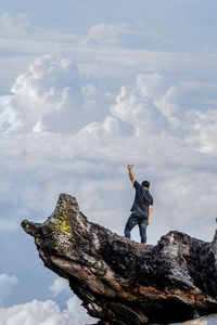 Man standing on rock against sky