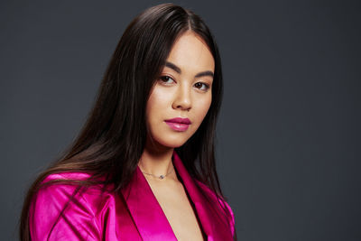 Portrait of young woman against black background