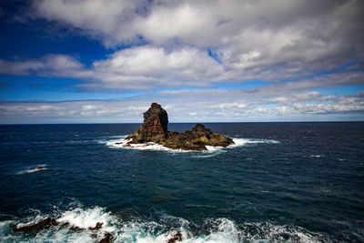 Rock formation in sea against sky