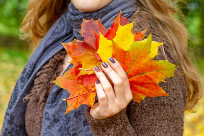 Close-up of woman holding maple leaf during autumn