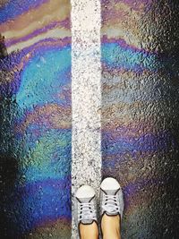 Low section of person standing by oil spill on street