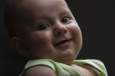 Portrait of cute baby boy against black background